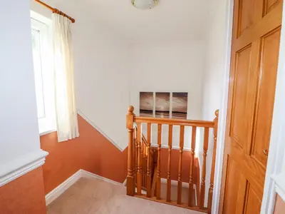 a hallway with a wooden staircase with a window at Annes Cottage in Keswick
