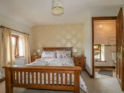 a bedroom with a large wooden bed with pillows at Poppy Cottage in Penrith