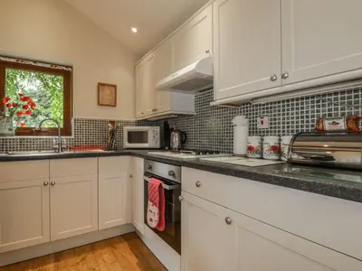 a kitchen with white cabinets and a sink and a microwave at Poppy Cottage in Penrith