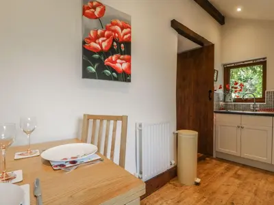 a kitchen with a table and a painting of flowers on the wall at Poppy Cottage in Penrith