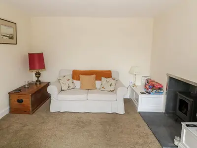 a living room with a white couch and a fireplace at 7 Cummertrees in Annan