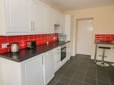 a kitchen with white cabinets and red tiles at 7 Cummertrees in Annan