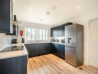 a kitchen with black cabinets and a stainless steel refrigerator at Oystercatcher in Drummore
