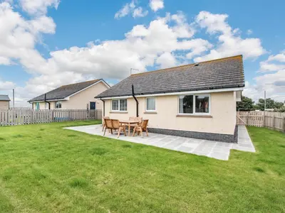 a house with a table and chairs in a yard at Oystercatcher in Drummore