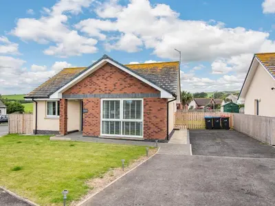 a brick house with a driveway in a yard at Oystercatcher in Drummore
