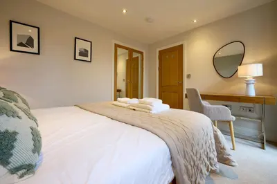 a bedroom with a white bed with a desk and a mirror at Riverside Park 3 in Keswick