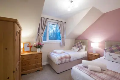 a attic bedroom with two beds and a window at Honeybee Cottage in Penrith