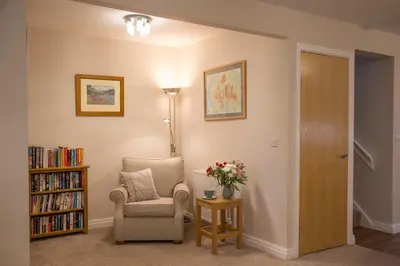 a living room with a chair and a book shelf at Honeybee Cottage in Penrith