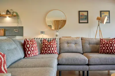 a living room with a gray couch with red and white pillows at Riverside Park 4 in Keswick