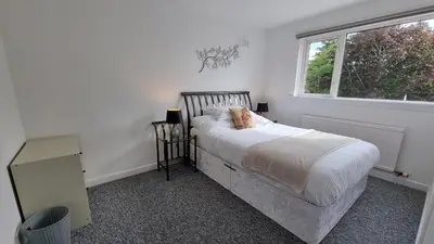 a white bedroom with a bed and a window at Rozelle Villa in Ayr