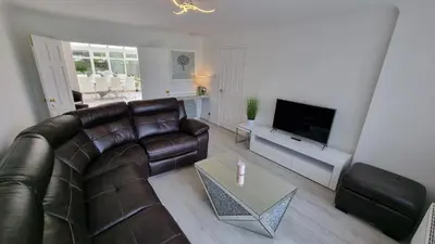 a living room with a leather couch and a television at Rozelle Villa in Ayr