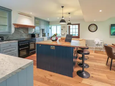 a kitchen with blue cabinets and a island in the middle at Flaska House in Penrith