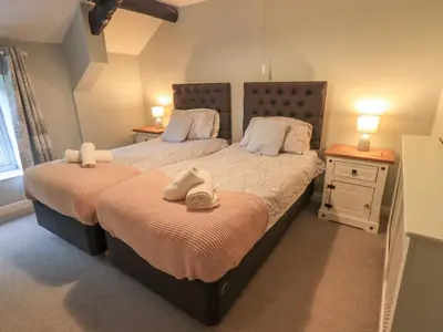 two beds in a bedroom with two tables and lamps at Flaska House in Penrith
