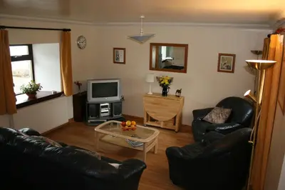 a living room with two leather chairs and a television at Corehouse Farm Cottages - Dairy, Granary & Sawmill in Lanark