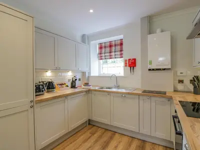 a kitchen with white cabinets and a window at North Firbank - Culzean Castle in Maybole