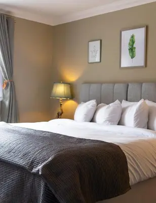 a bedroom with a large bed with white pillows at Bojangles Guest House in Gretna Green