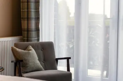 a chair with a pillow sitting in front of a window at Bojangles Guest House in Gretna Green