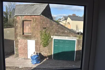 a brick building with a garage with a green garage door at Milo's place is a home from home in Egremont