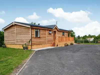 a log cabin with a driveway in front of it at The Alpaca Lodge in Rowrah