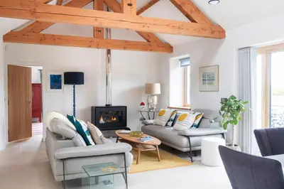 a living room with white walls and wooden beams at The Stables - Luxury Cottage in Dumfries