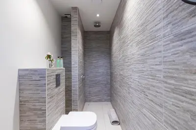 a bathroom with a toilet and a stone wall at The Stables - Luxury Cottage in Dumfries