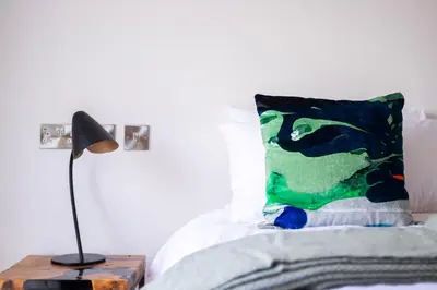 a bedroom with a bed with a pillow and a lamp at The Stables - Luxury Cottage in Dumfries