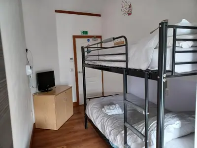 a room with two bunk beds and a television at Voyage Hostel - Rooms with Shared Kitchen in Douglas