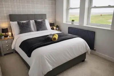 a bedroom with a bed with two pairs of shoes on it at Beautiful Beach Front Cottage in Allonby
