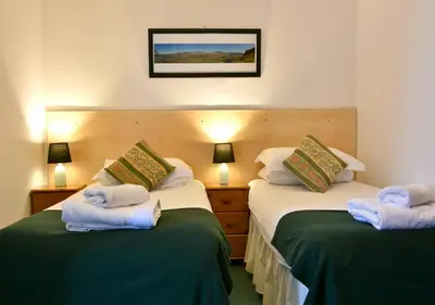 two beds in a hotel room with towels on them at Brook House Inn in Eskdale