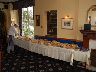 a man standing in front of a table with food at Brook House Inn in Eskdale