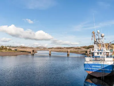 a boat in the water with a bridge in the background at Auchengool House in Kirkcudbright
