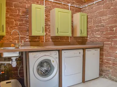 a laundry room with a sink and a washing machine at Monkwood Cottage in Hale