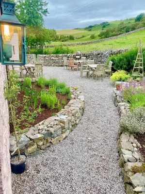 a garden with a stone wall and tables and plants at Buittle Castle Exclusive Use- Stay in your own Castle! in Castle Douglas