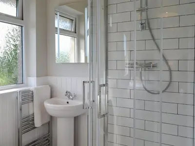 a white bathroom with a shower and a sink at Culbae Cottage in Whauphill
