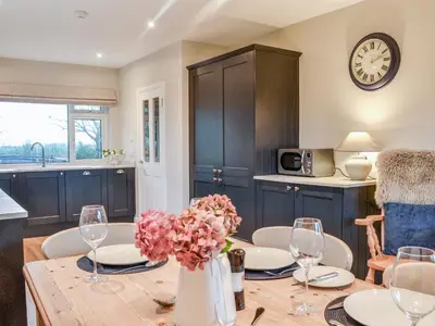 a kitchen with a table with a vase of flowers at Culbae Cottage in Whauphill