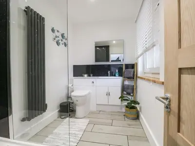 a bathroom with a toilet and a glass shower at Swaledale Watch House Annexe in Wigton