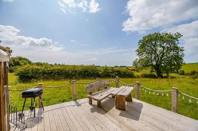 a wooden deck with a bench and a grill at The Kites Rest at Castle Creavie Farm in Kirkcudbright