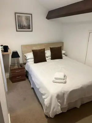 a bedroom with a large white bed with towels on it at Rooms at the Bush in Wigton