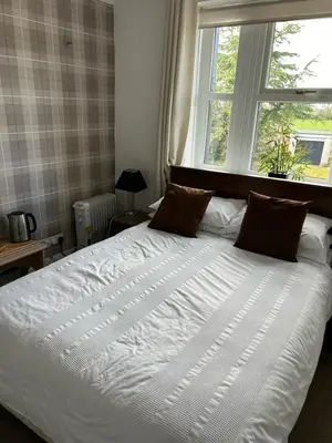a large white bed in a bedroom with a window at Rooms at the Bush in Wigton