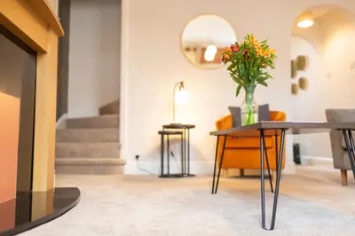 a living room with a table with a vase of flowers on it at Logan House, Modern and Spacious Townhouse close to City Centre in Carlisle