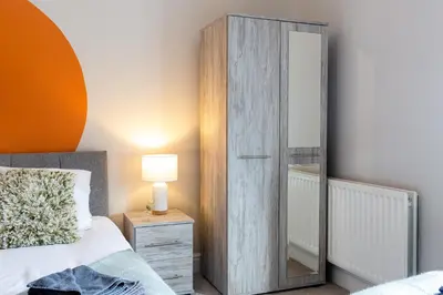 a bedroom with a large wooden cabinet next to a bed at Logan House, Modern and Spacious Townhouse close to City Centre in Carlisle