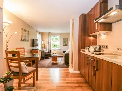 a kitchen with a table and a living room at Cosy Corner in the Lakes in Penrith