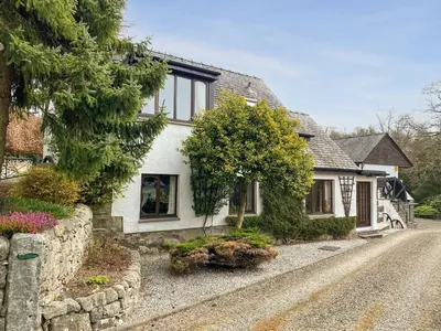 a white house with a stone wall at Forge Mill Cottage in Dalbeattie