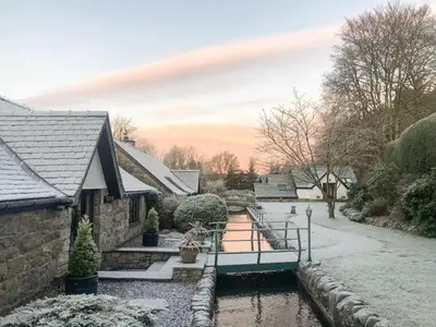 a house with snow on the ground and a canal at Forge Mill Cottage in Dalbeattie