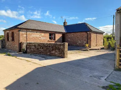 a brick house with a blue roof on a street at Low Moat in Canonbie