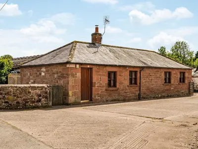 an old brick building with a wooden door at Low Moat in Canonbie