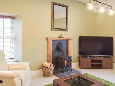 a living room with a fireplace and a flat screen tv at Dairy Cottage - Uk39522 in Maybole