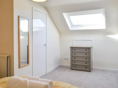 a bedroom with a window and a dresser and a mirror at Cairncroft Cottage in Colfin