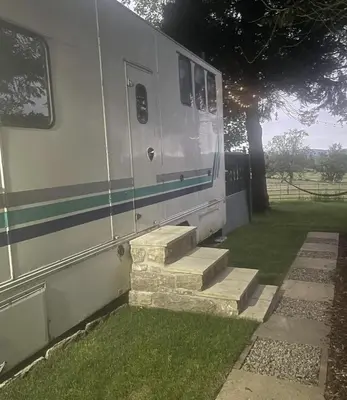a white trailer with stairs next to a tree at Dobbin the horse box in The Lake District in Cockermouth