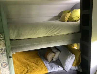 two bunk beds in a room with yellow and white pillows at Dobbin the horse box in The Lake District in Cockermouth